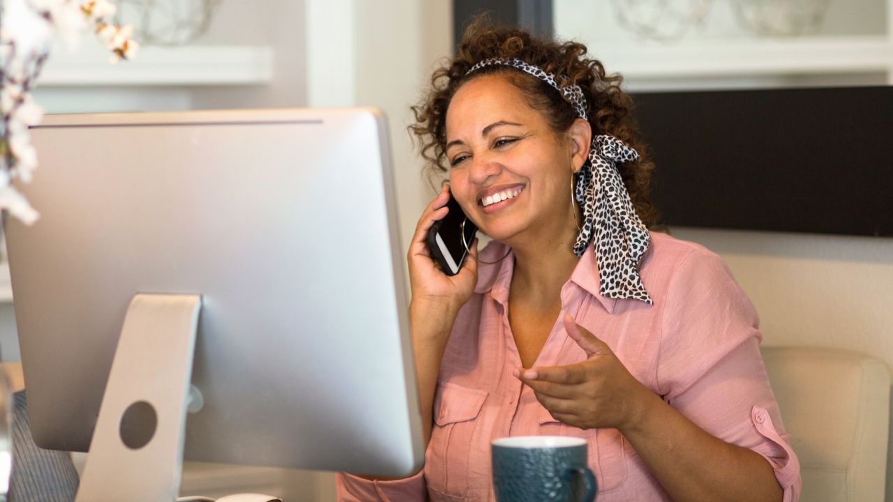 Woman working on computer on sofa with daughter by her side.